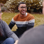 happy group of young adults sitting outside