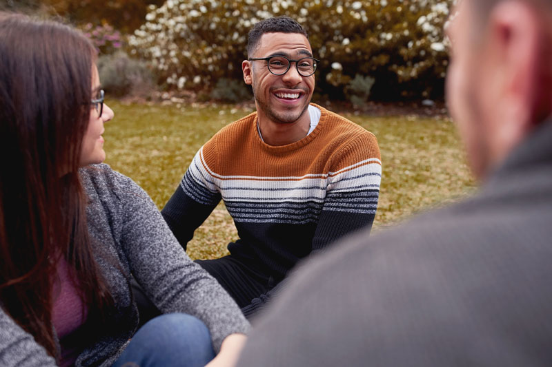 happy group of young adults sitting outside