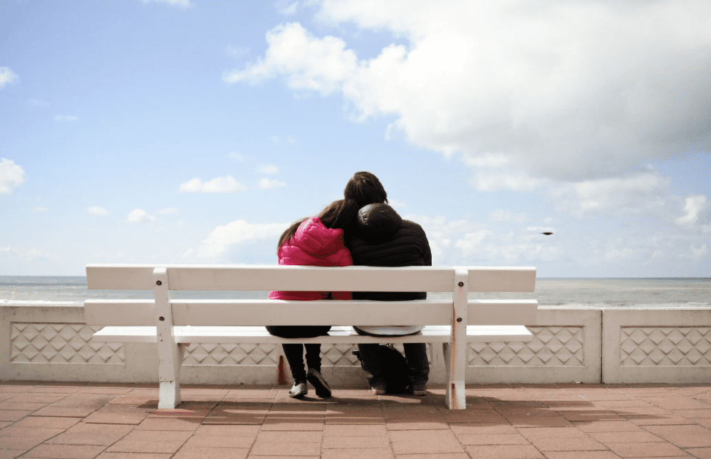 A couple sitting on a bench.