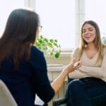 Woman talks with a therapist in a bright office, sitting comfortably during a counseling session.